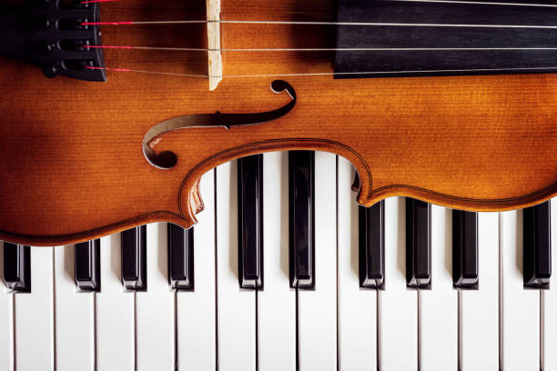 Violin on top of piano keys  background Violin on top of piano keyboard background with copy space for music concept conservatory education building stock pictures, royalty-free photos & images