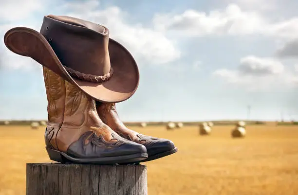 Photo of Cowboy hat and boots at ranch, country music festival live concert or line dancing concept
