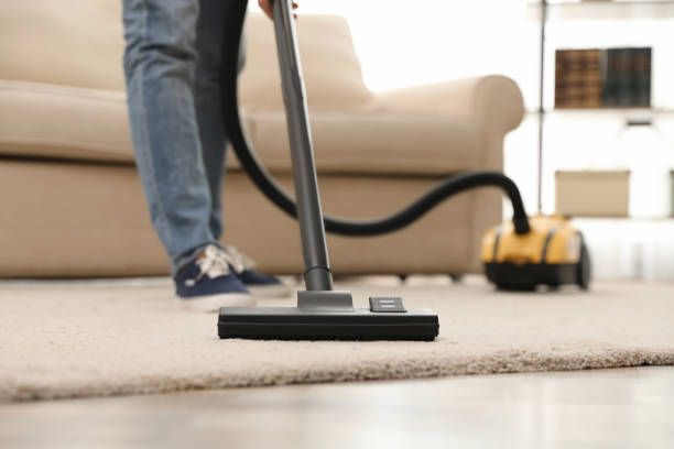 istock Young man using vacuum cleaner at home, closeup 1336662728
