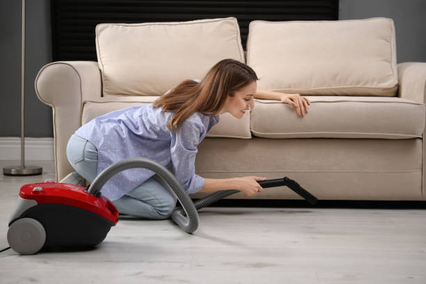 istock Young woman using vacuum cleaner at home 1336662959