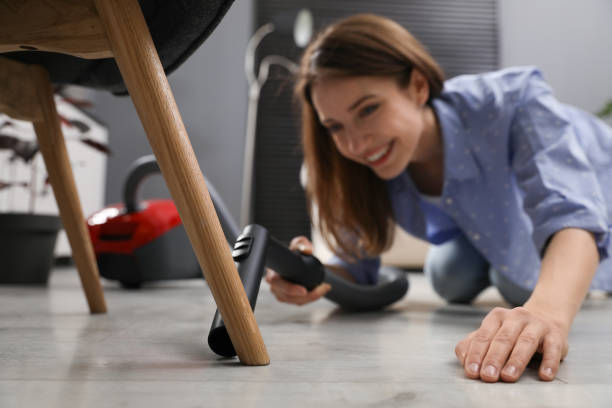 istock Young woman using vacuum cleaner at home 1336663310