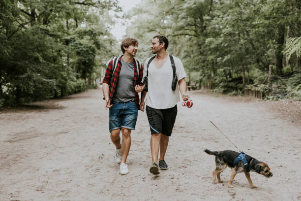 istock Couple walking with dog in public park 1336666957