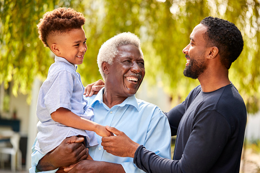 Joyful young African American dad playing with kids, piggybacking two siblings on neck. Happy excited kids riding together on strong daddy shoulders, playing active games, having fun