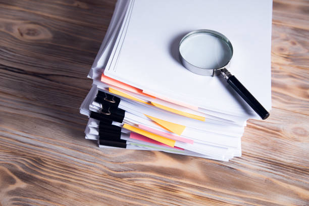 istock magnifier on stock of papers 1336672875