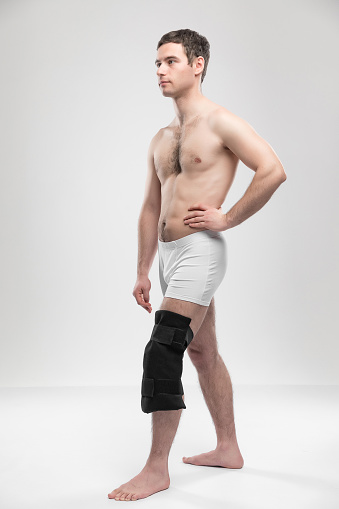 Studio portrait of adult sports man with reusable post-injury ice-pack with liquid gel. Rehabilitation and recovery concept with copy space