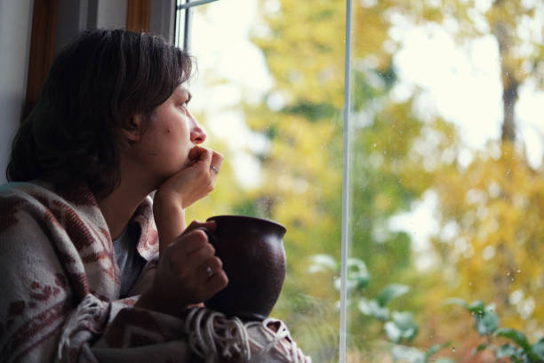 Fall melancholy mood concept. Wistful woman sitting near window and looking at autumn landscape outside in rainy day. Copy space. Fall melancholy mood concept. Wistful woman sitting near window and looking at autumn landscape outside in rainy day. Copy space. seasonal affective disorder stock pictures, royalty-free photos & images