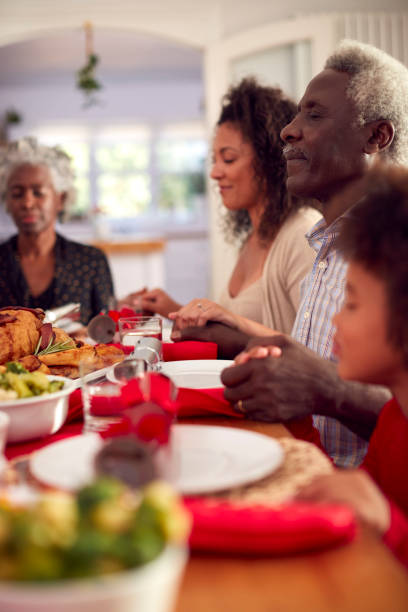 istock Multi Generation Family Hold Hands Around Table At Home Saying Grace Before Eating Christmas Meal 1336680305