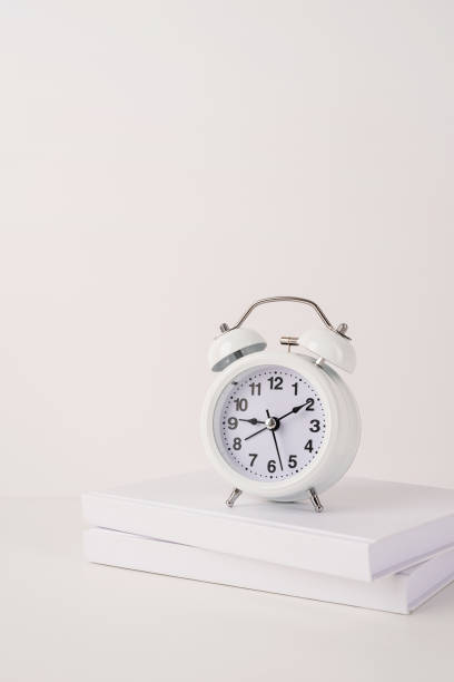 istock White alarm clock on stack of books, mockup design 1336680854