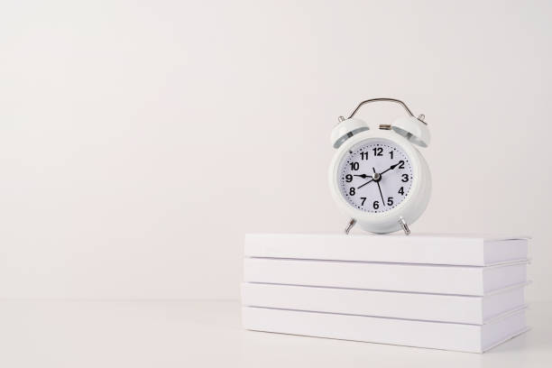 istock White alarm clock on stack of books, mockup design 1336681012
