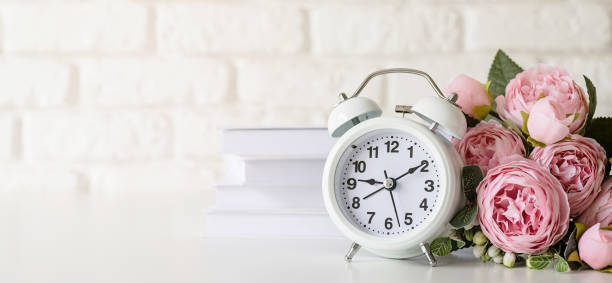 istock White retro alarm clock on white brick wall with books and peonies with copy space 1336681197