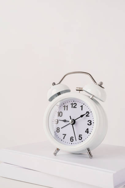 istock White alarm clock on stack of books, mockup design 1336681420
