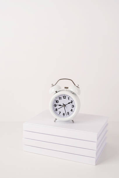 istock White alarm clock on stack of books, mockup design 1336681520