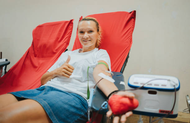 Young caucasian woman with toy heart in the hand donates blood stock photo