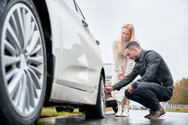 istock Young man helping charming woman to fix car wheel. 1336682664