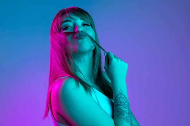One young beautiful girl having fun isolated on blue studio background in neon light filter. Concept of human emotions, facial expression, youth, sales, ad.