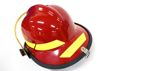 Portrait of a Caucasian fireman wearing his firefighter suit, standing next to a fire engine at the station. He is holding his firefighter helmet.