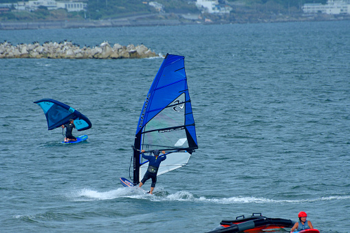 Many young people are enjoying windsurfing on a fine, windy Sunday afternoon at Miura Beach, Miura City, Kanagawa Prefecture. Miura Beach is located at the entrance to Tokyo Bay from the Pacific Ocean.