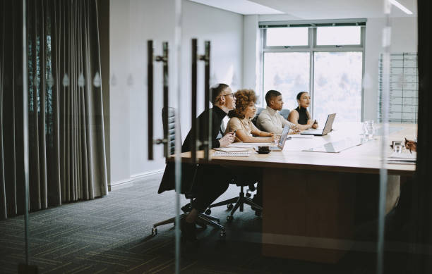 scatto di un gruppo di uomini d'affari che hanno una riunione in una sala riunioni al lavoro - table board room laptop office foto e immagini stock