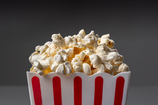 Popcorn in a red and white container on a gray background.