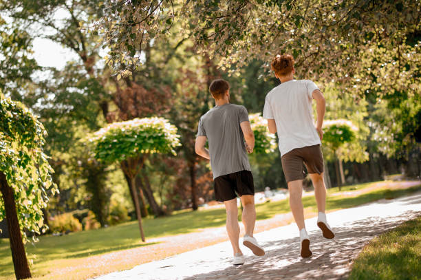 istock View from back of guys running in park 1336698270