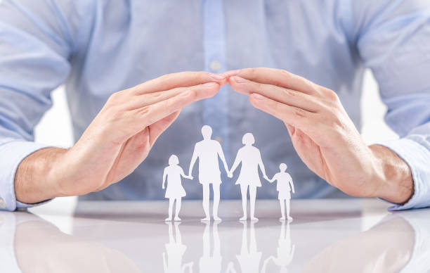 Family care concept. Hands with paper silhouette on table. Hands with cut out paper silhouette on table. Family care concept. life insurance stock pictures, royalty-free photos & images