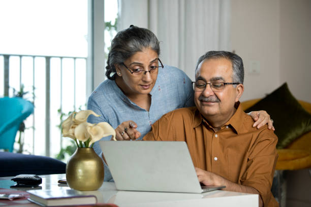 senior couple using laptop while working on home budget - computer two people asian ethnicity women imagens e fotografias de stock