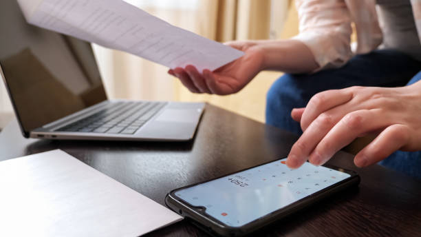 istock Woman uses calculator on cellphone to count big payments 1336703838