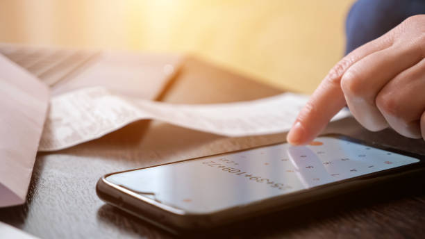 istock Woman uses calculator on cellphone to count big payments 1336703840