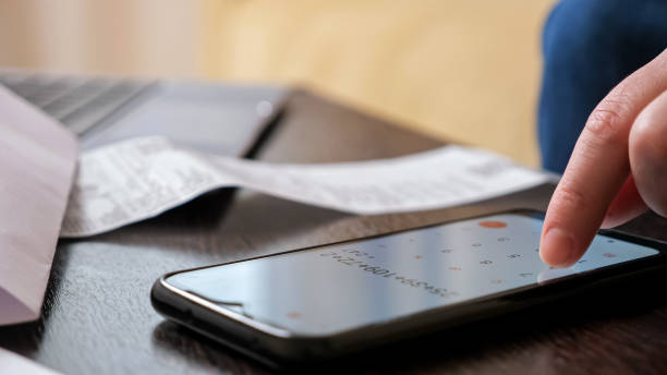 istock Woman uses calculator on cellphone to count big payments 1336703847