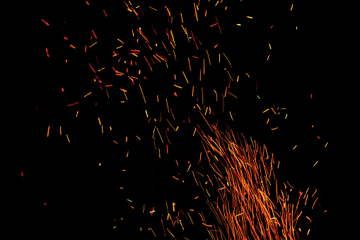 Burning red hot sparks fly away in a night sky from a large camp fire copy space image.