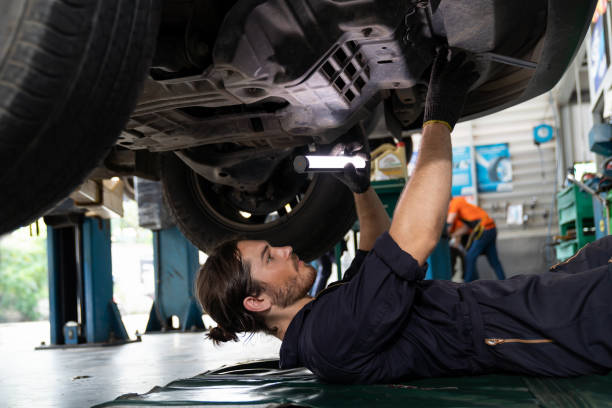 istock Male car mechanic worker working using wrench tool for repair, maintenance underneath lifted car. Mechanic vehicle service checking under car in garage. Auto car repair service, maintenance concept 1336708111
