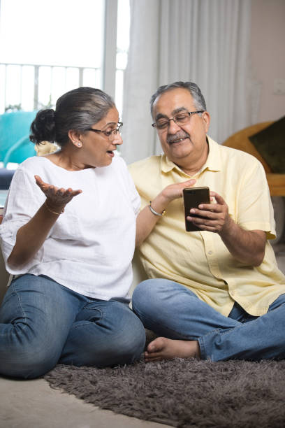 istock Old couple enjoying using mobile phone at home 1336708140