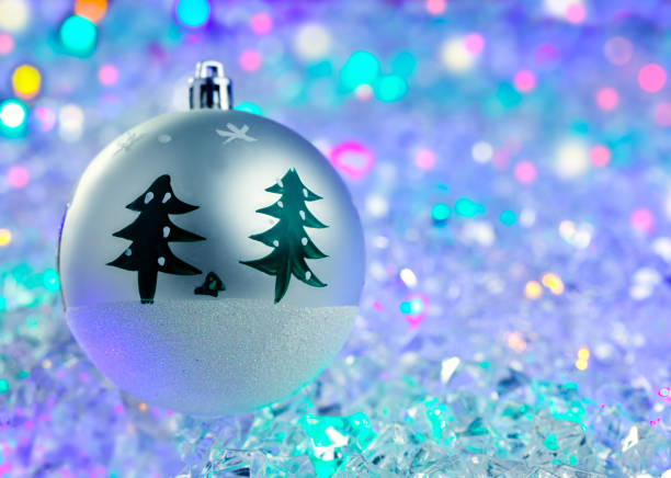 A beautifully decorated Christmas tree glows with festive ornaments, set against bokeh background of soft, twinkling lights.