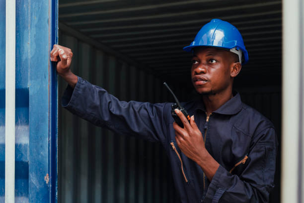 istock black african amarican man worker working control loading freight containers at commercial shipping dock. cargo freight dock and import export logistic concept. 1336713216