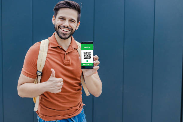 istock Young man holing a mobile phone and on device screen is digital Covid Vaccination Passport 1336715445