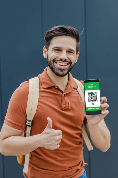 istock Young man holing a mobile phone and on device screen is digital Covid Vaccination Passport 1336715586