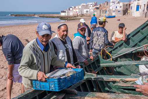 Souss-Massa, Morocco - march 02, 2016: Group of fishermen around a boat on the beaches of the town of Tifnit