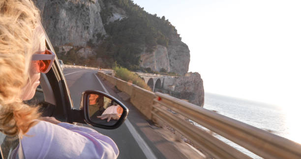 istock Woman enjoys passenger seat while driving along coastal road 1336724315