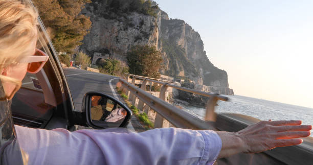 istock Woman enjoys passenger seat while driving along coastal road 1336724327