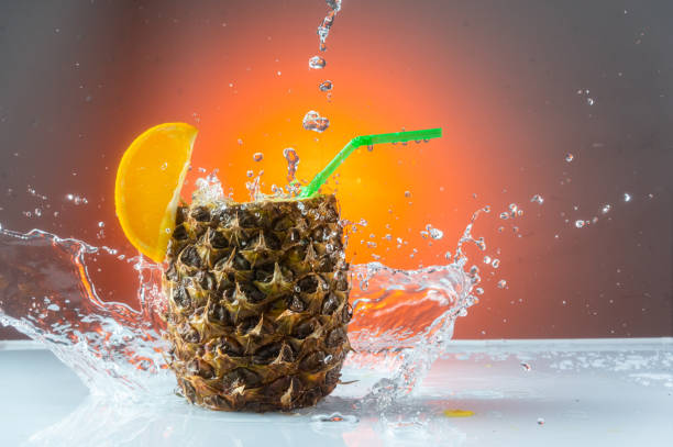 istock Splashing water around the pineapple. Pineapple cocktail and splash. Red background. 1336727846