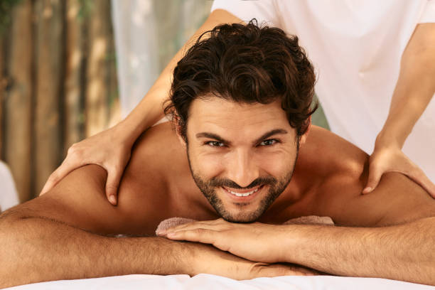 Thai massage therapy. Portrait of handsome man while shoulders and back massage with masseuse hands at wellness spa