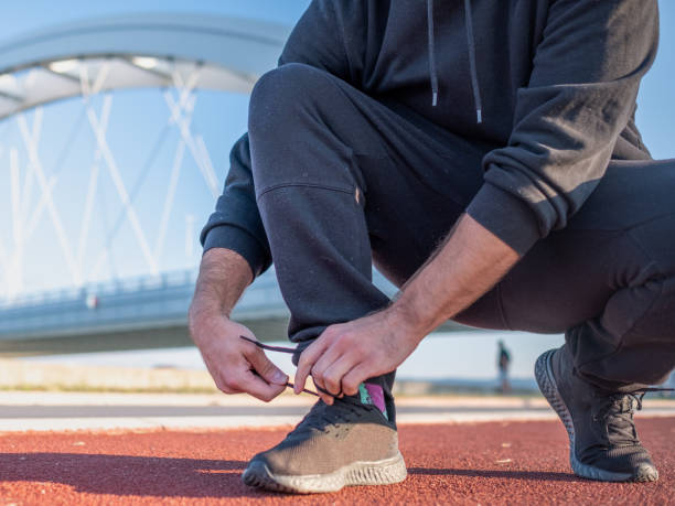 istock man wearing black tracksuit tying his shoelaces 1336731051
