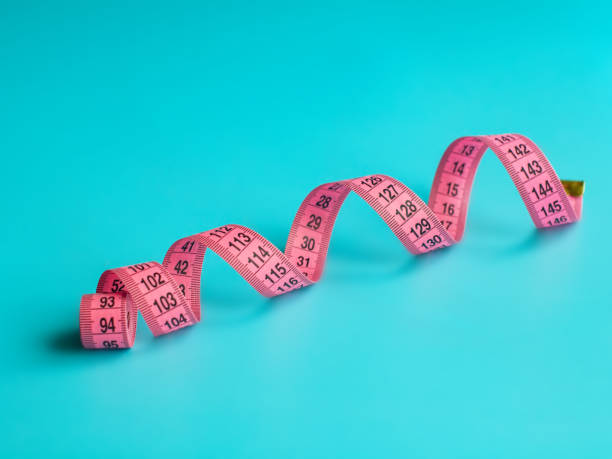 istock Pink centimeter tape measure on blue background 1336731973