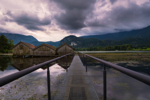 View on boat houses at lake Kochelsee on cloudy summer day, vanishing point perspective