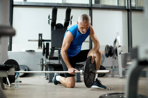 istock Mature athlete adjusting weight plate on a barbell in a gym. 1336734291