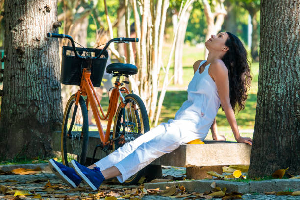 jeune femme assise dans le parc à côté du vélo - parc flamengo photos et images de collection