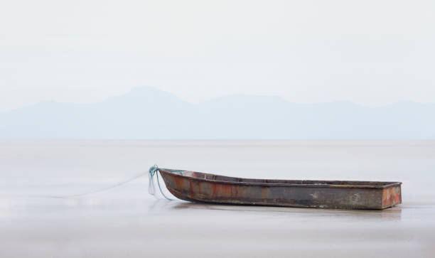 Long exposure of a rusty fishing boat stranded on the sea in a shine day The photograph was taken with the long exposure technique in order to isolate a small rusty fishing vessel from the sunny beach scene. floating platform stock pictures, royalty-free photos & images