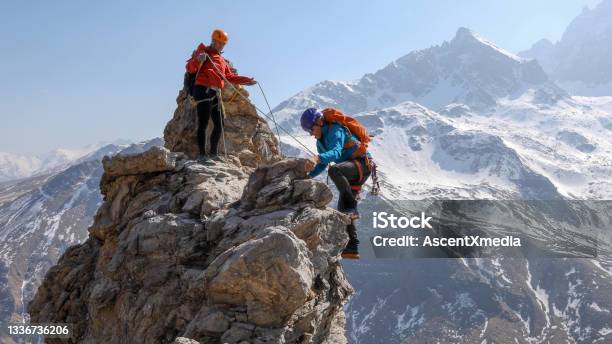 Mountaineering Couple Scramble To Summit Together Stock Photo - Download Image Now - Mountain Climbing, Risk, Mountain