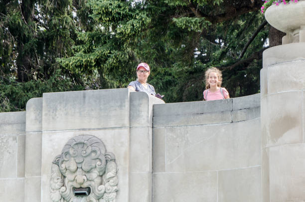 istock Woman and girl standing behind a concrete wall 1336736232