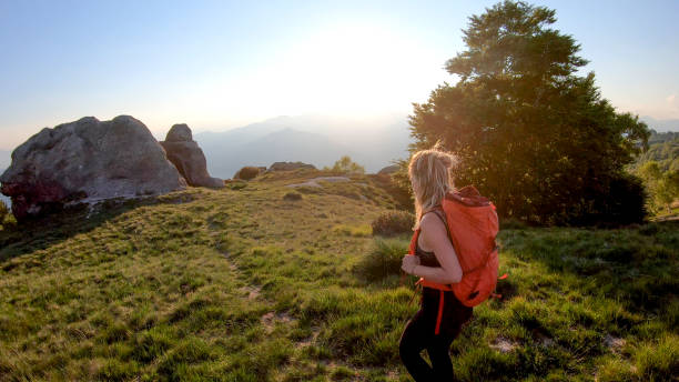 istock Young woman backpacker hikes into sunlight on a mountain ridge 1336737305